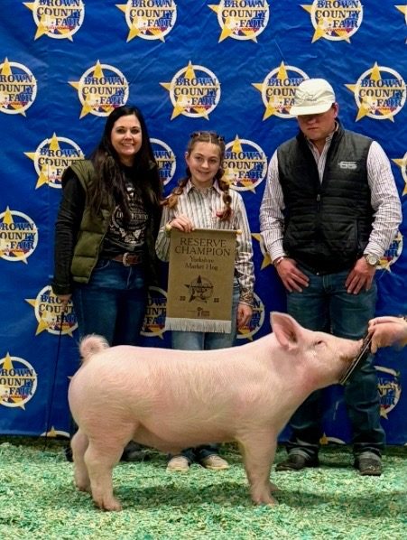 Kelby with her Reserve Champion Yorkshire market hog at the 2025 Brown County Youth Show, with Amber and the judge